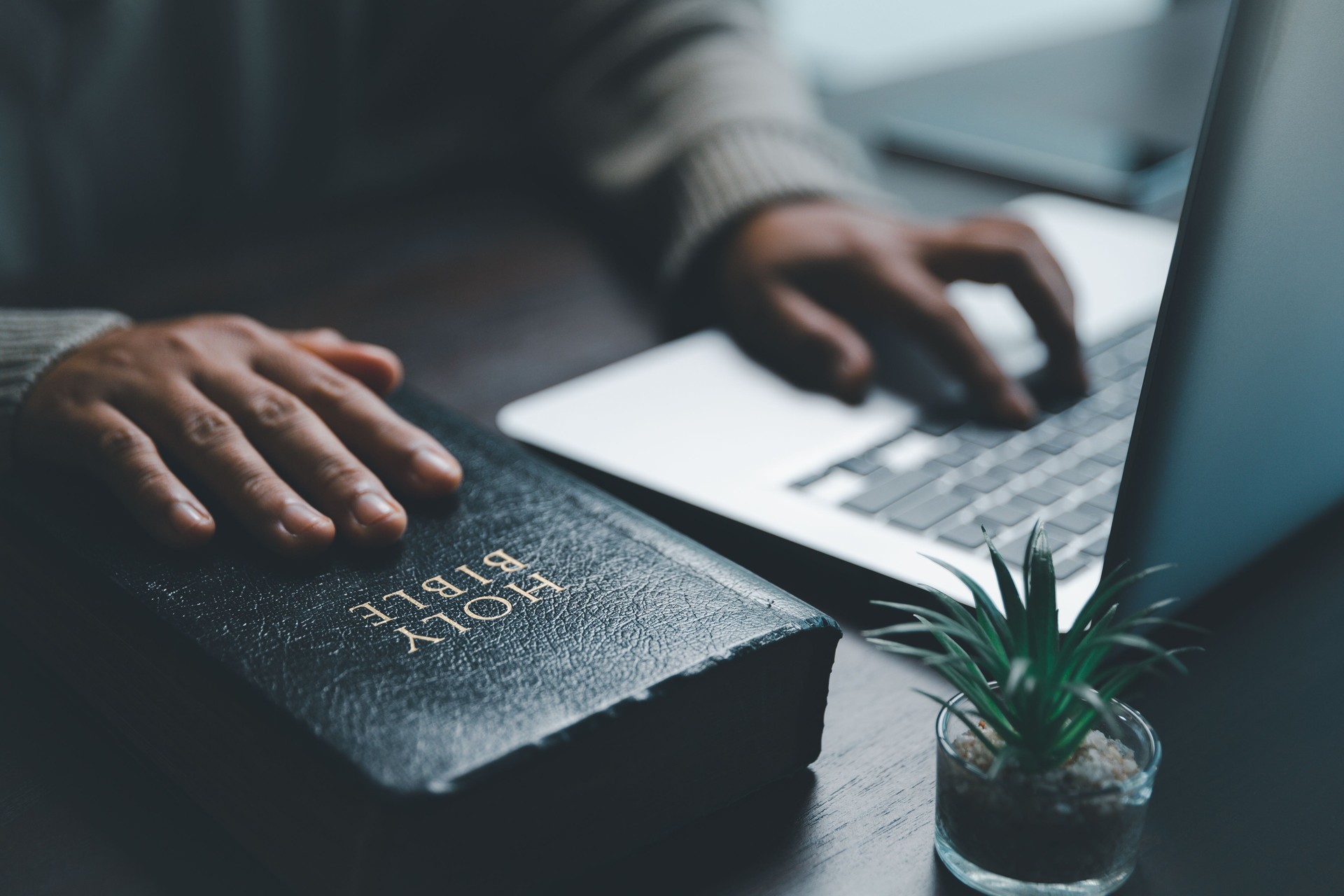 Christian online technology concept. Hands praying of christian with digital computer laptop, Online live church for sunday service. Asian catholic woman are reading Holy bible book and online study.