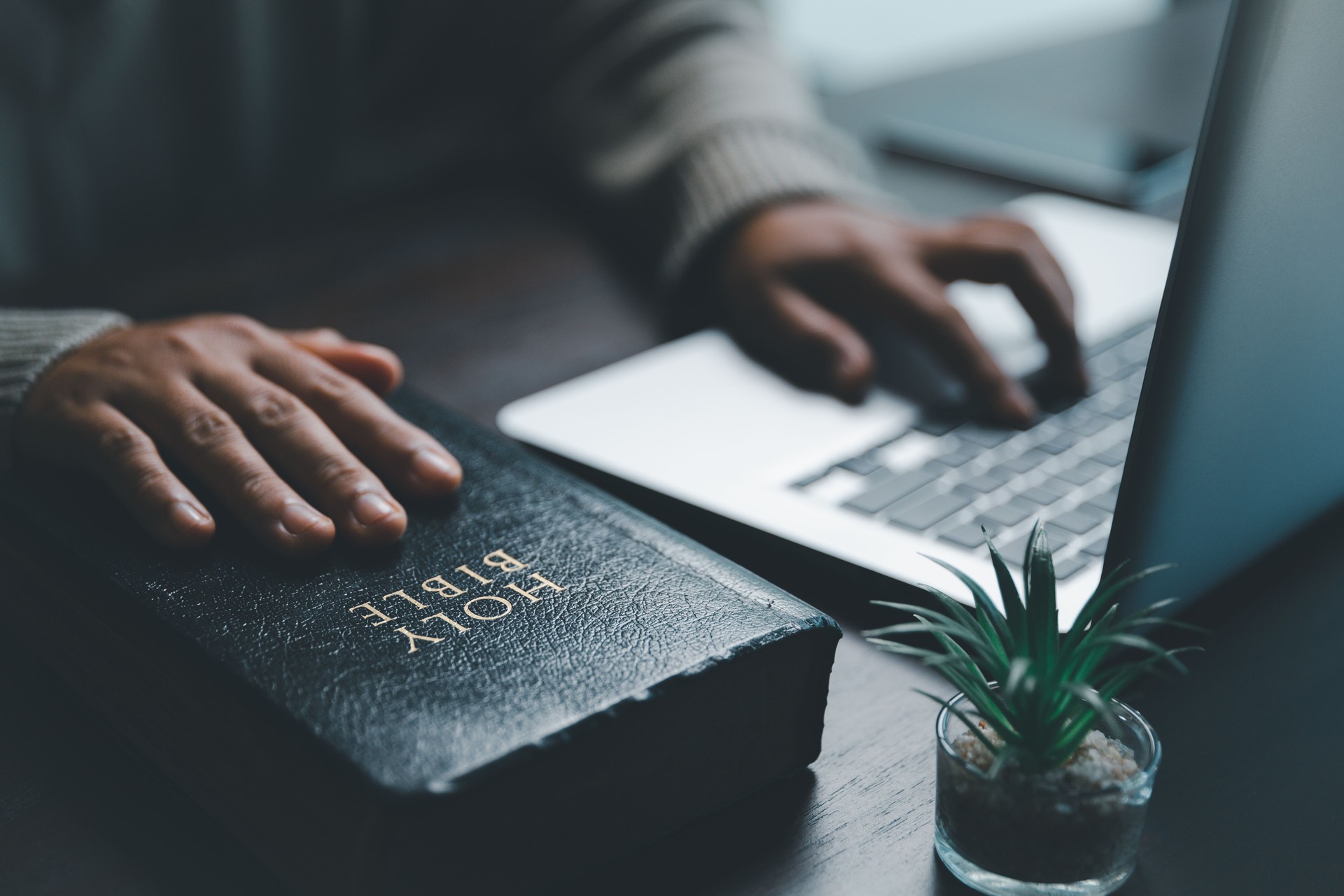 Christian online technology concept. Hands praying of christian with digital computer laptop, Online live church for sunday service. Asian catholic woman are reading Holy bible book and online study.